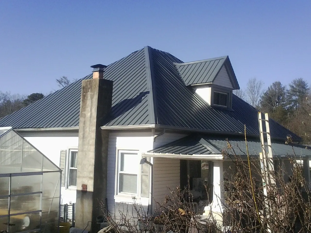 Dark blue standing seam metal roof on a white farmhouse with dormer — Slate & Tile Roof Repair by Roofing Brothers in Newtown
