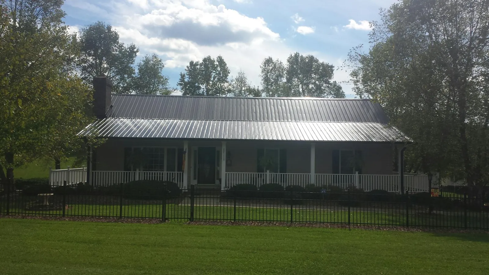 Gray metal roof on a brick ranch with a full width front porch — Gutter Guard Installation work by our crew in Newtown